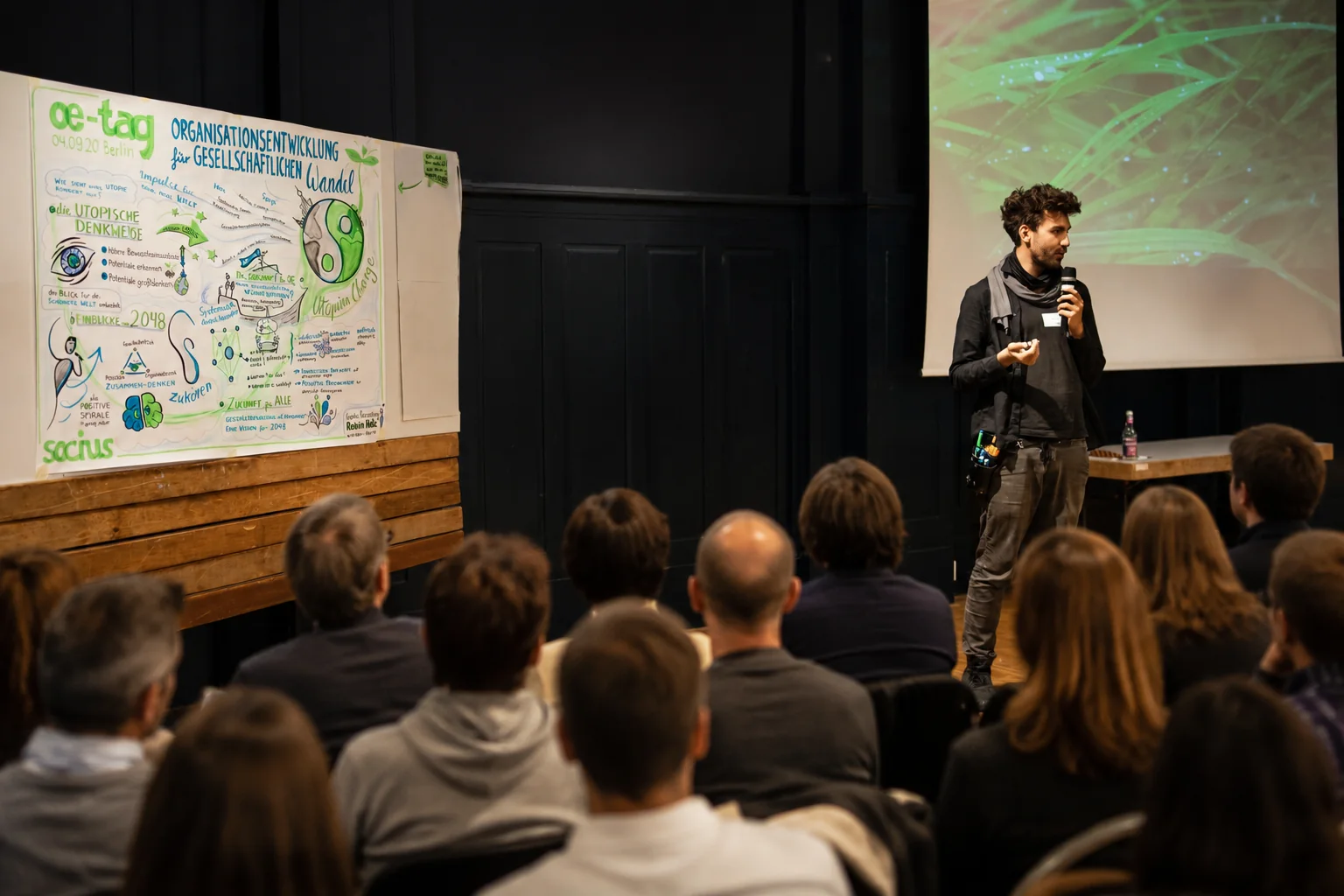 Robin Hotz moderiert vor Publikum bei einer Konferenz